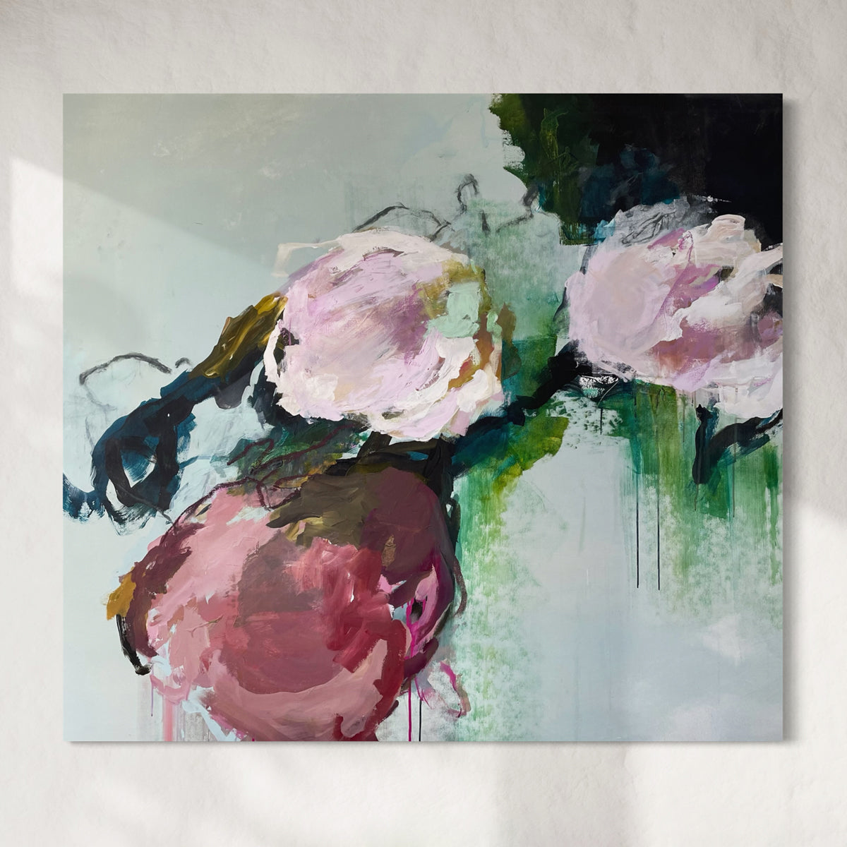 Abstract painting with pink and green colors on a textured wall.