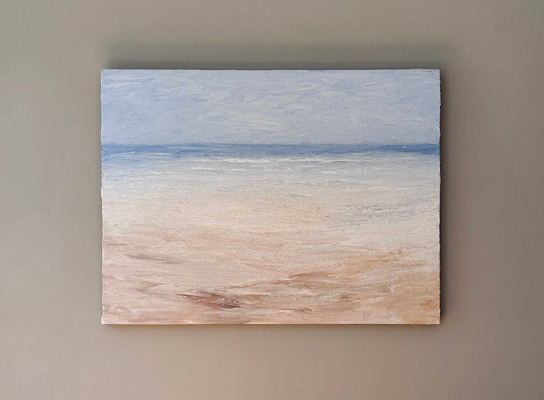 An abstracted coastal painting hangs on a white wall.