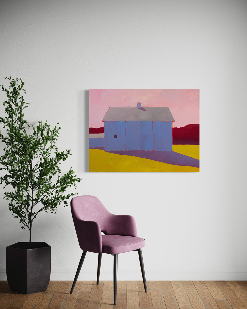 A warm-toned landscape painting hangs on a white wall above a pink chair and large floor plant.