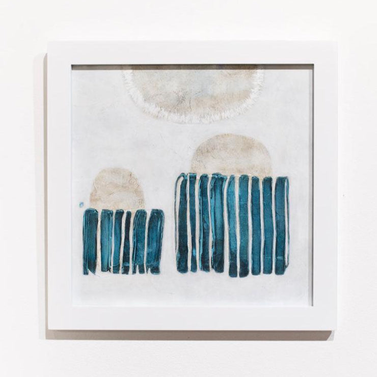 A blue, white, and beige abstract painting framed in a white frame hangs on a white wall.