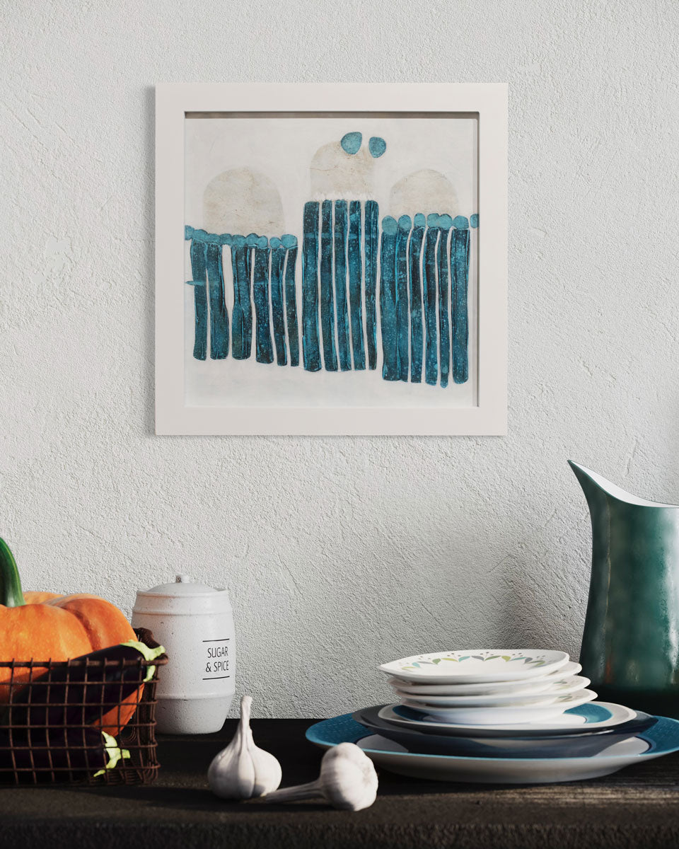 A framed blue and white abstract painting hangs on a textured wall above dishes, a vegetable basket and sugar jar.