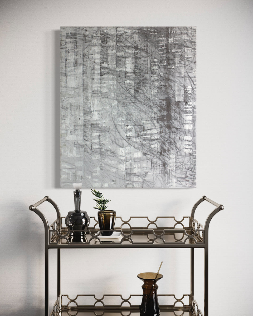 A black and silver abstract painting hangs on a white wall above a modern chrome bar cart.