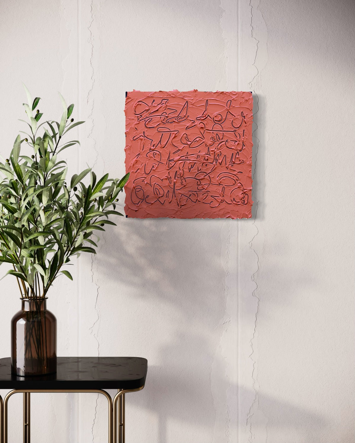 A abstract painting with navy text based line drawings on a muted coral-red background, displayed on a white wall above a black side table with a green plant in a dark amber vase.