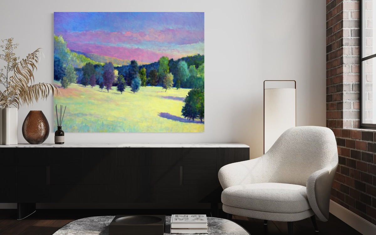 Modern living room with a painting of a landscape on the wall, a white armchair, and decorative items.
