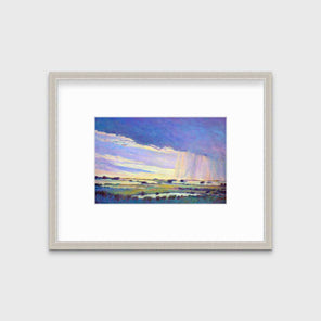 A purple, yellow and blue abstract landscape print in a silver frame with a mat hangs on a white wall.