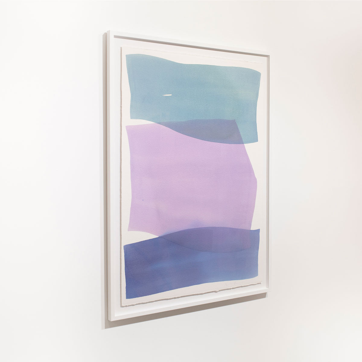 An abstract blue and violet abstract watercolor painting framed in a white frame hangs on a white wall.