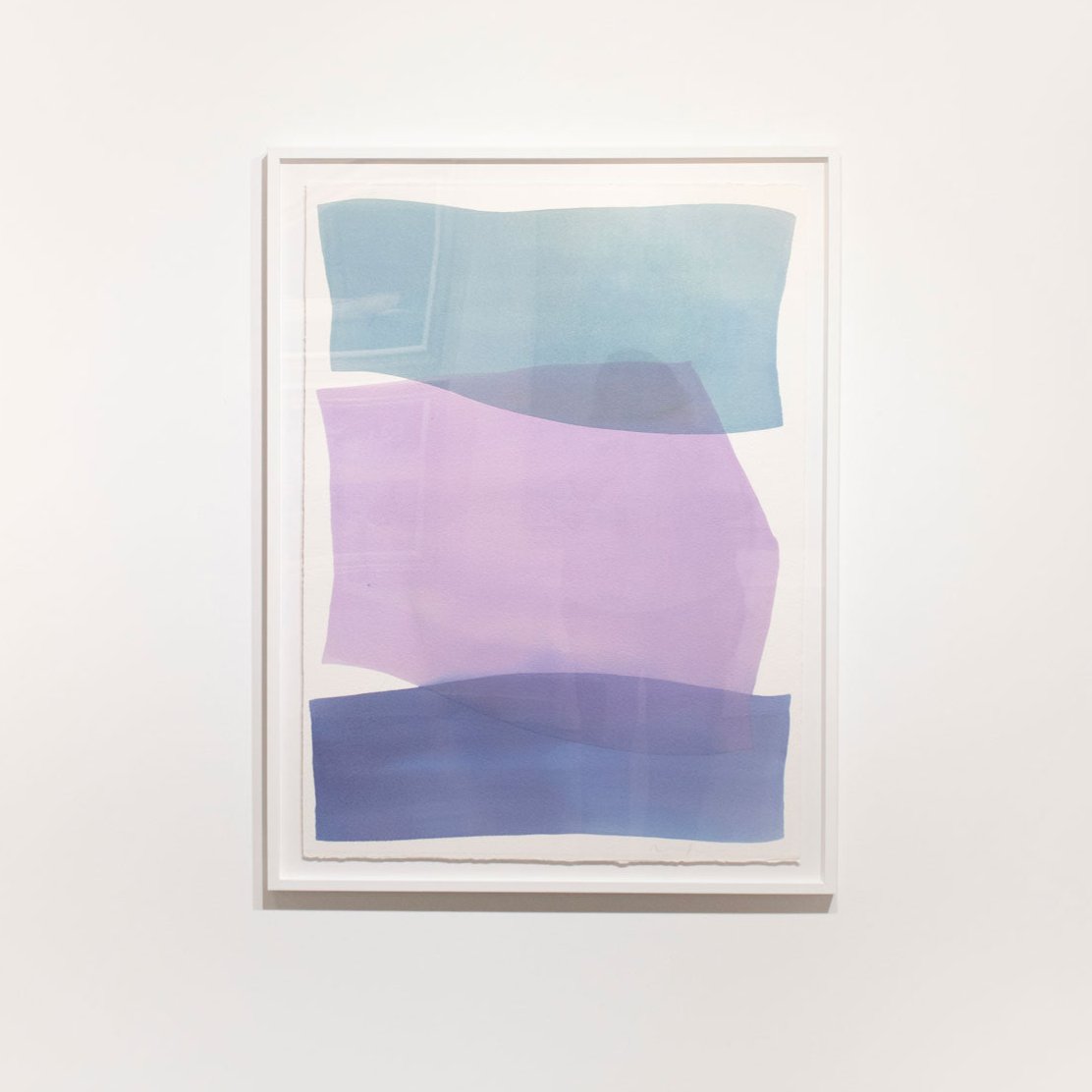 An abstract blue and violet abstract watercolor painting framed in a white frame hangs on a white wall.