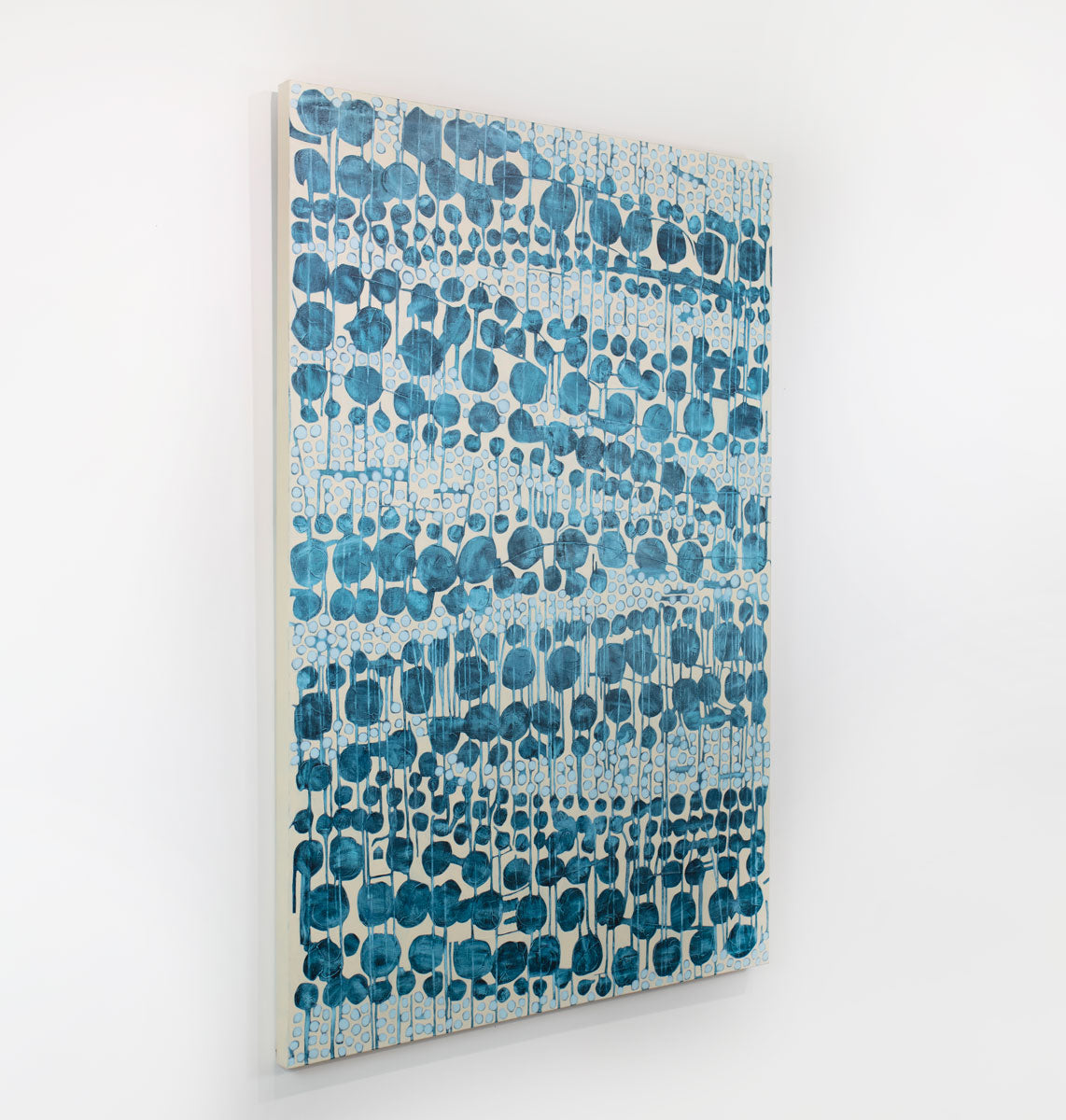 An abstract blue and beige painting hangs on a white wall.