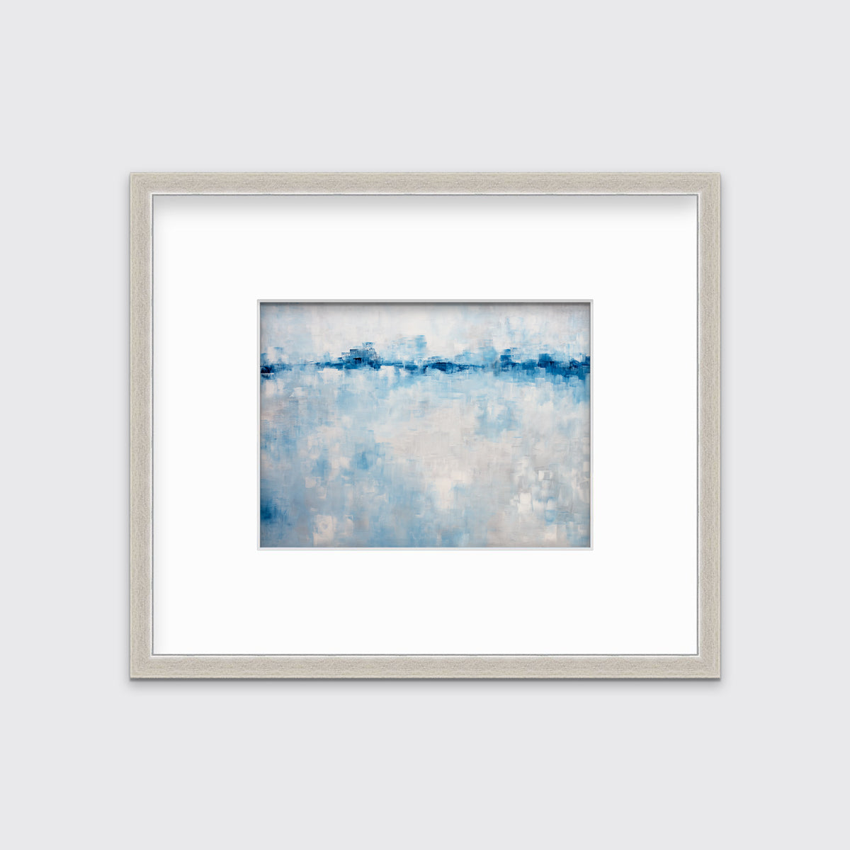 A blue and white abstract print in a silver frame with a mat hangs on a white wall.