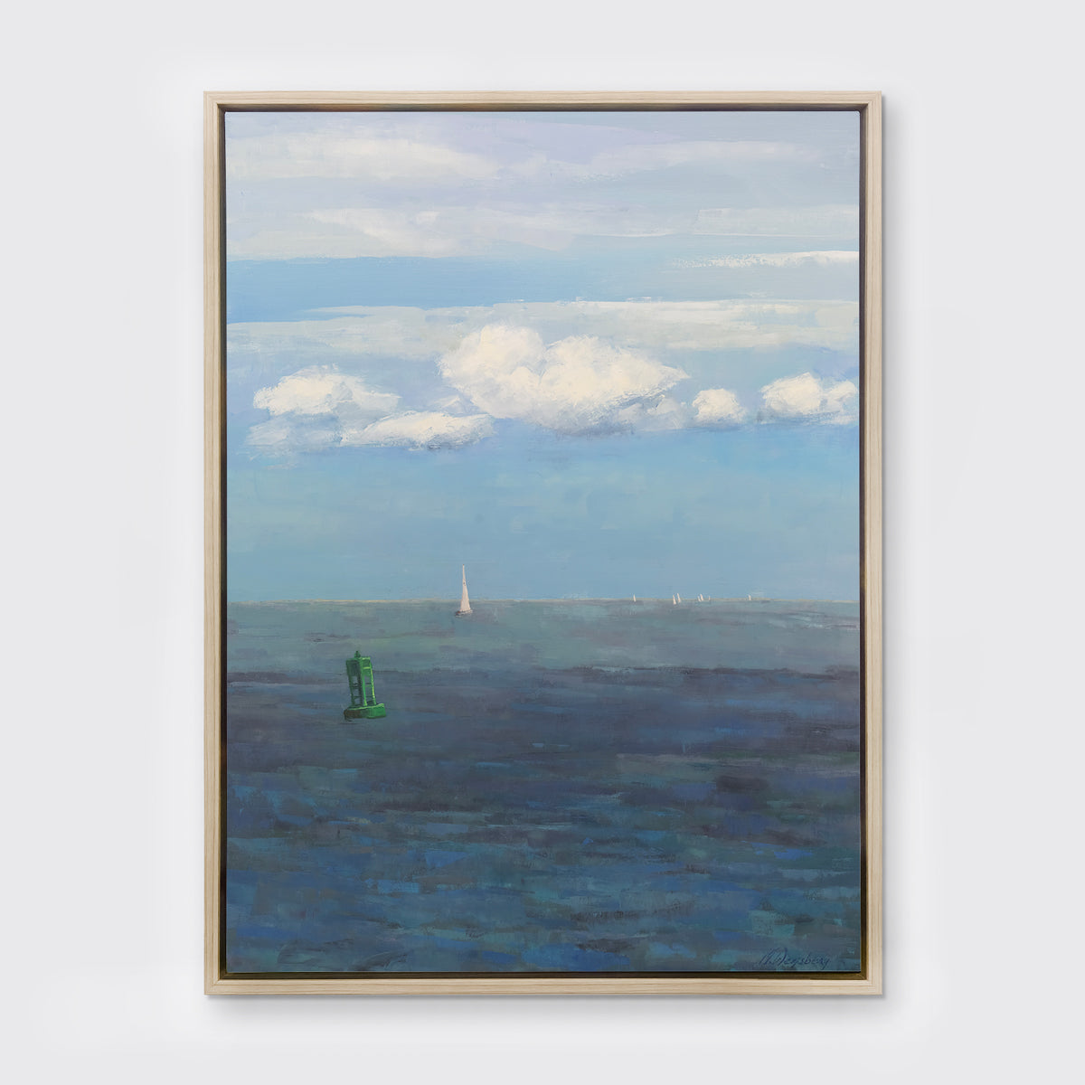 A coastal seascape print in a white oak wood floater frame hangs on a white wall.