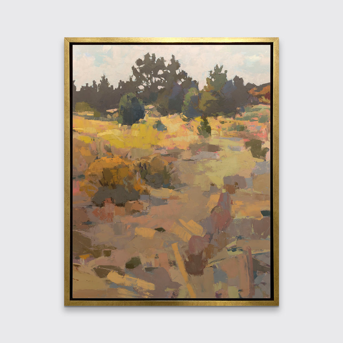 An earth-toned abstracted landscape art print framed in a gold frame hangs on a white wall.