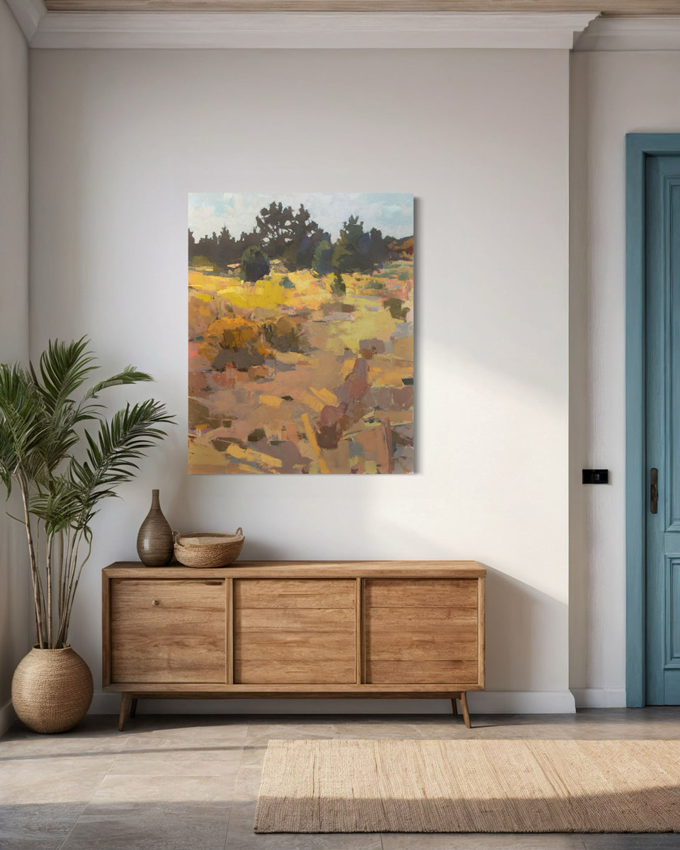 An abstracted landscape painting hangs on a white wall above a wooden credenza.