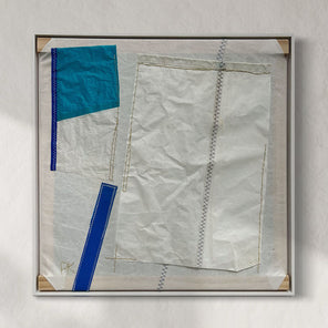 A framed abstract artwork featuring pieces of upcycled dacron sail with varying shades of blue and white, wax thread, and wood.