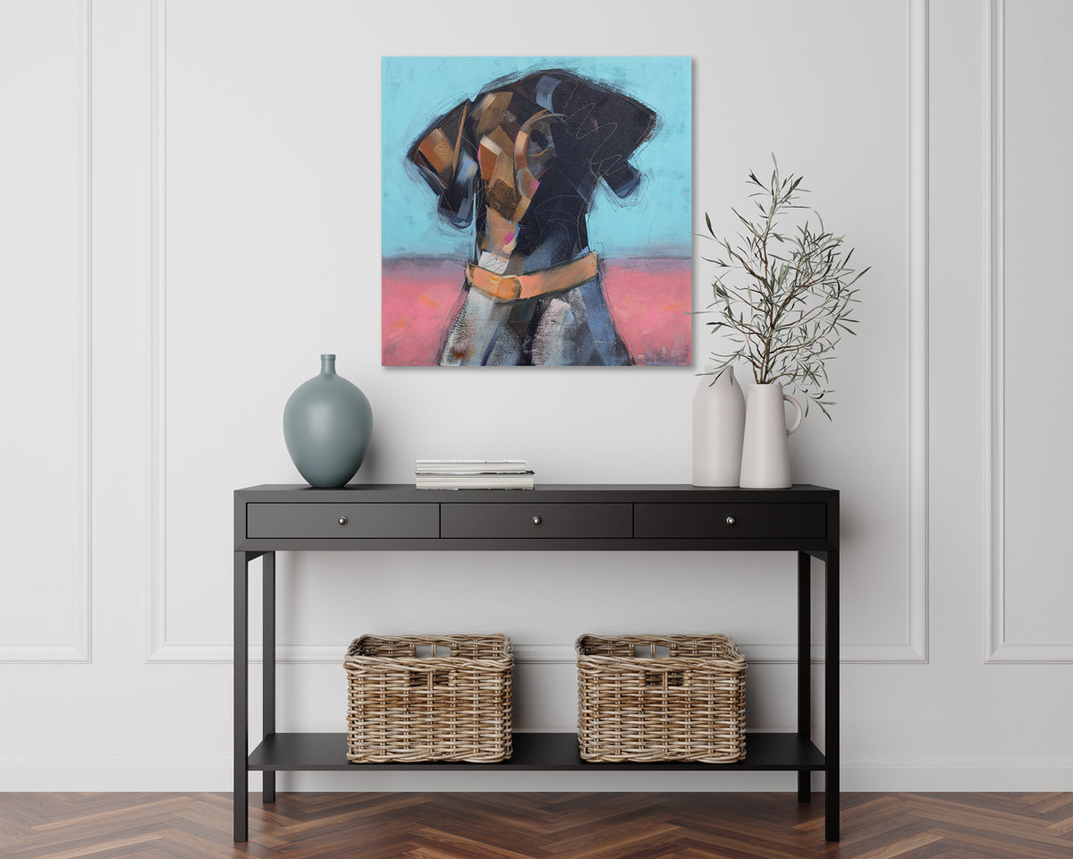 A blue, brown, and pink painting of an abstracted dog hangs on a white wall above a modern black console table with modern table decor.