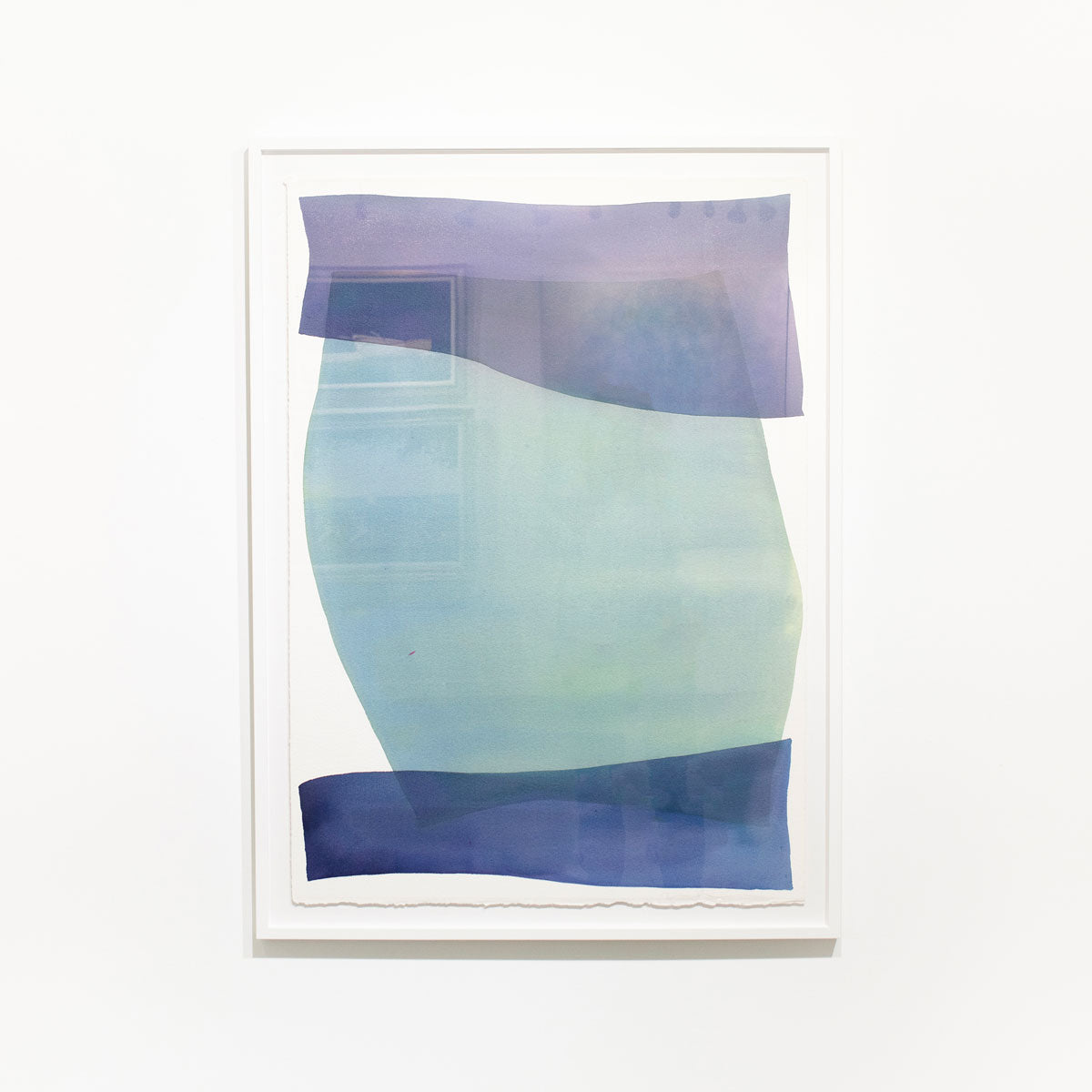 A green and blue abstract watercolor painting framed in a white frame hangs on a white wall.