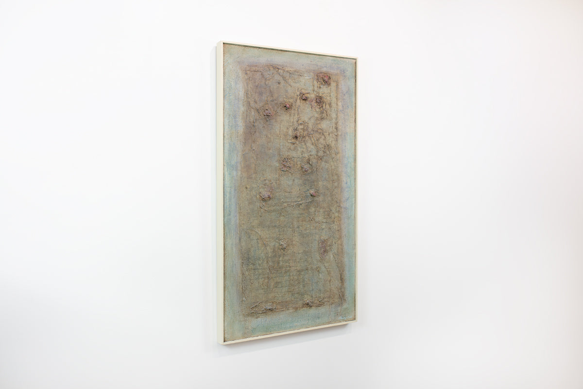 A green and brown abstract painting hangs on a white wall.