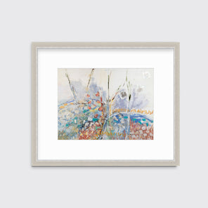 A multicolored abstract floral print in a silver frame with a mat hangs on a white wall.