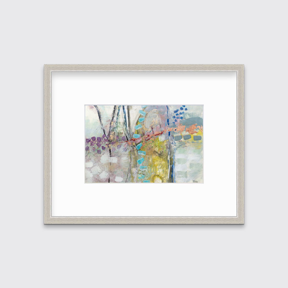 A multicolored abstract print in a silver frame with a mat hangs on a white wall.