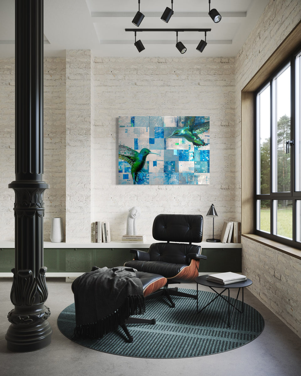 An abstract painting of two humming birds, hangs on a light grey wall, on a white brick wall with a black leather chair.