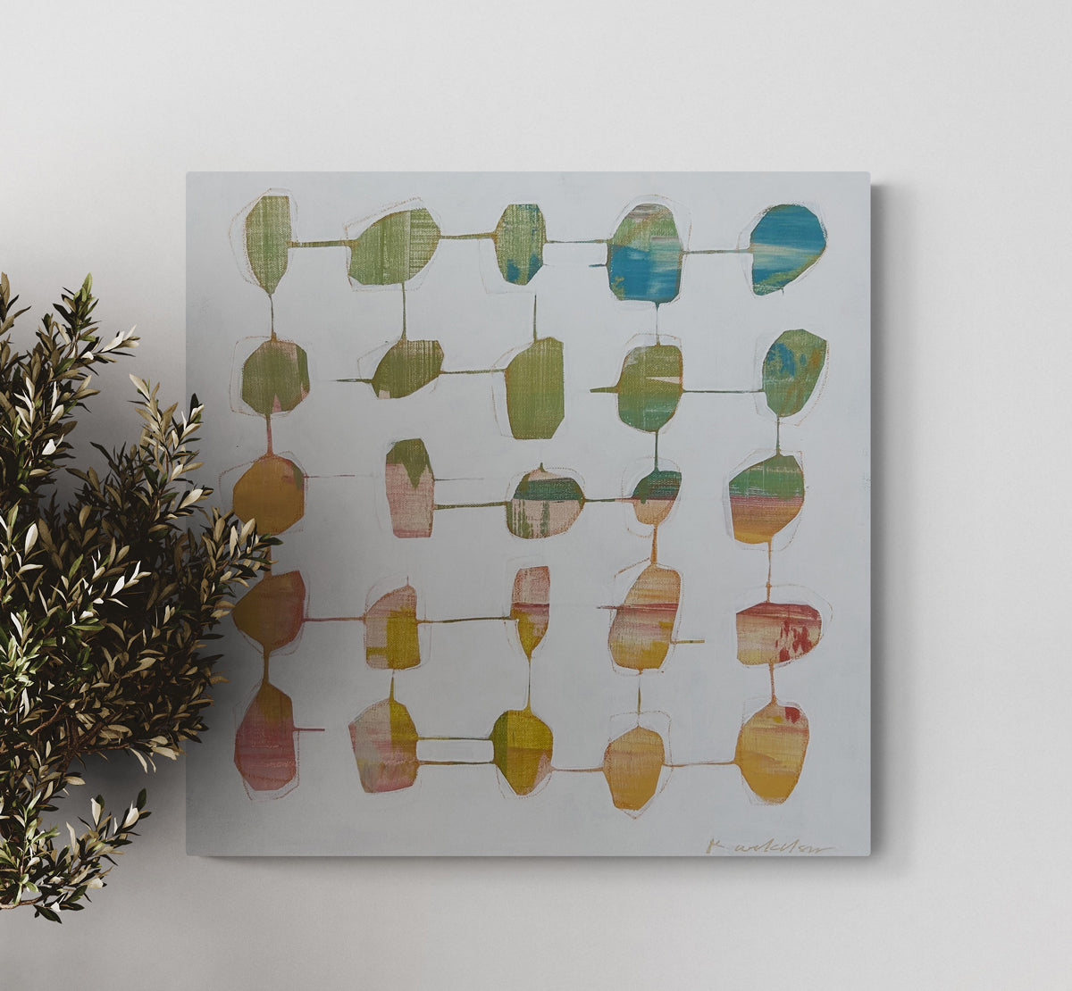 An abstract painting hangs on a white wall next to a plant.