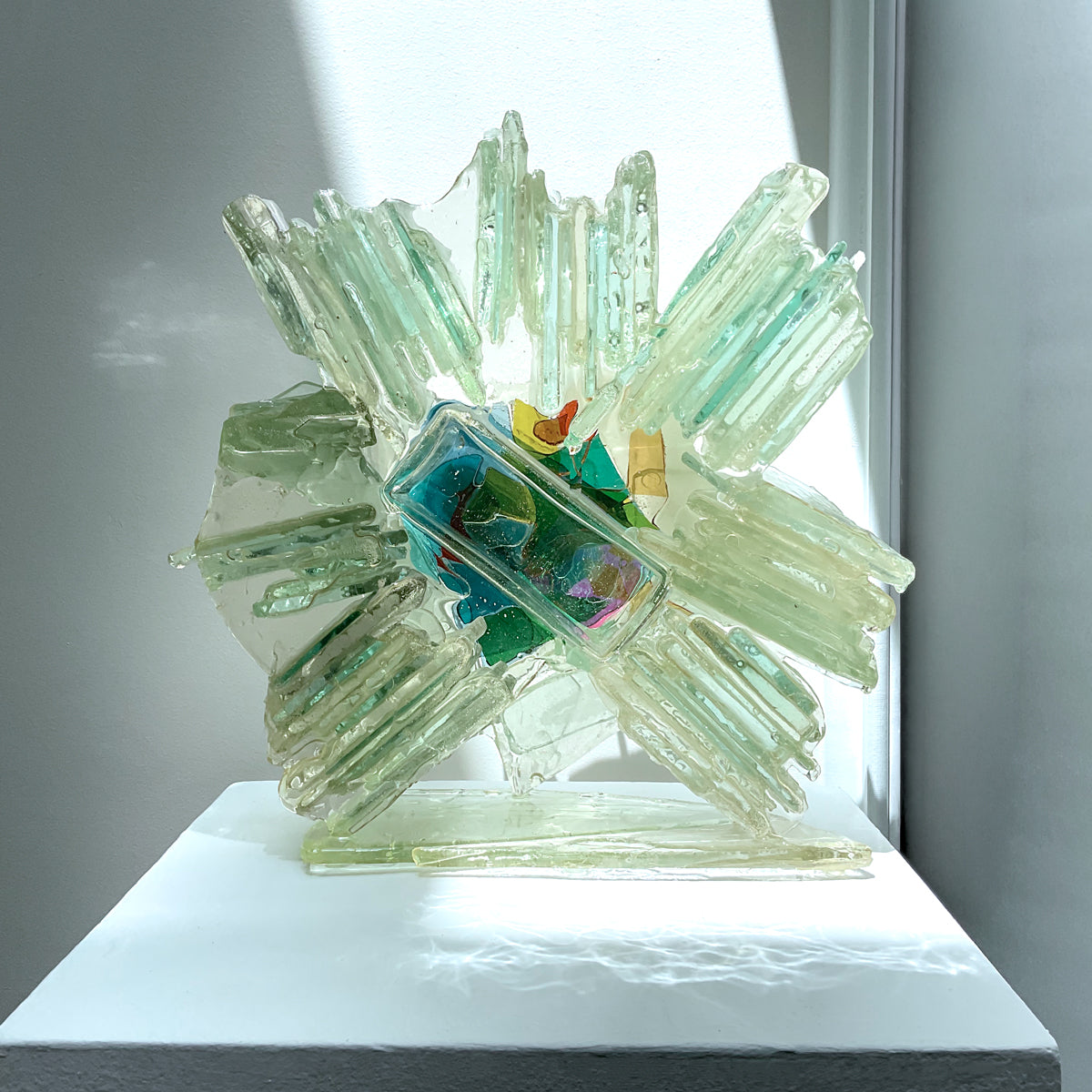 Glass sculpture with geometric design on a white platform.