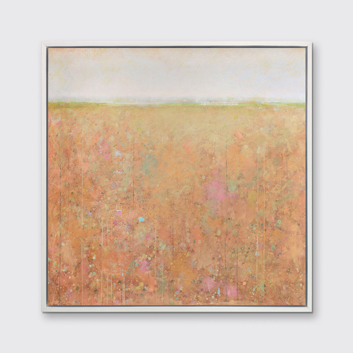 A orange, light green, light blue and pink abstract landscape print in a white floater frame hangs on a white wall.