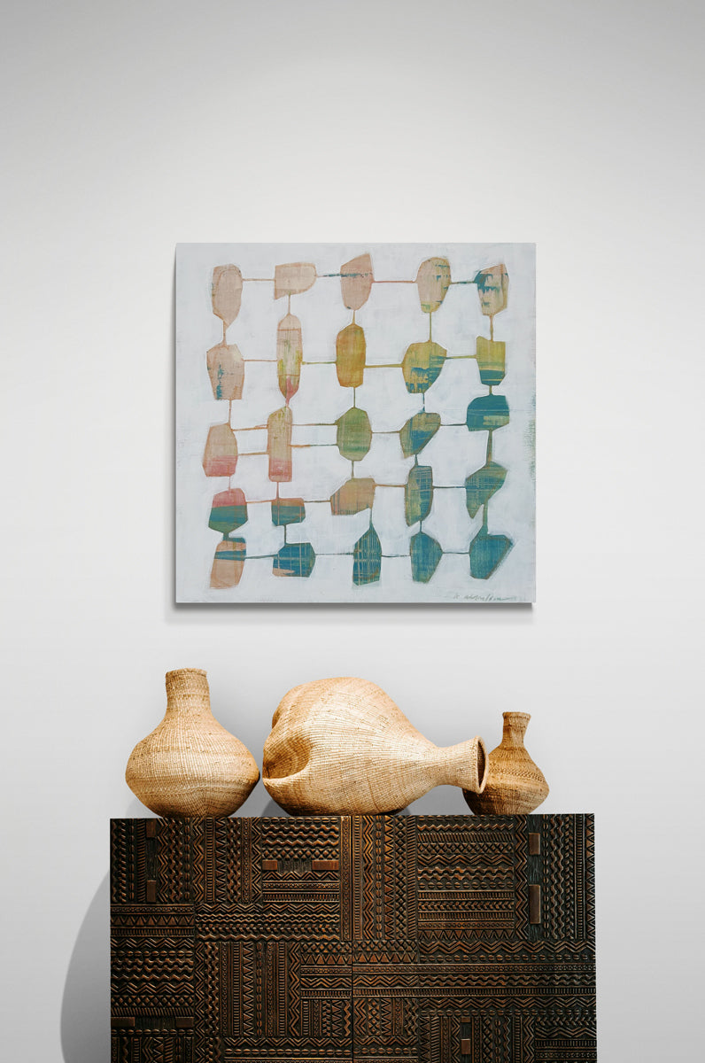 An abstract painting hangs on a white wall above an ornate table with wicker table decor.