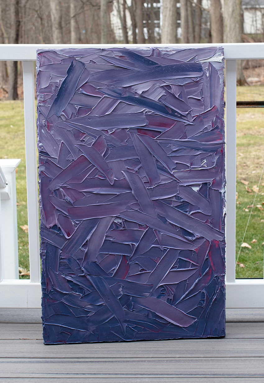 A tonal purple and pink thickly textured abstract painting by Teodora Guererra sits on a deck outside in the natural light.