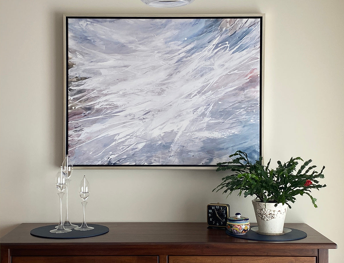 Abstract painting on a wall above a wooden console table with decorative items.