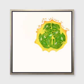 An abstract print of a fruit framed in a silver floater frame hangs on a light wall.