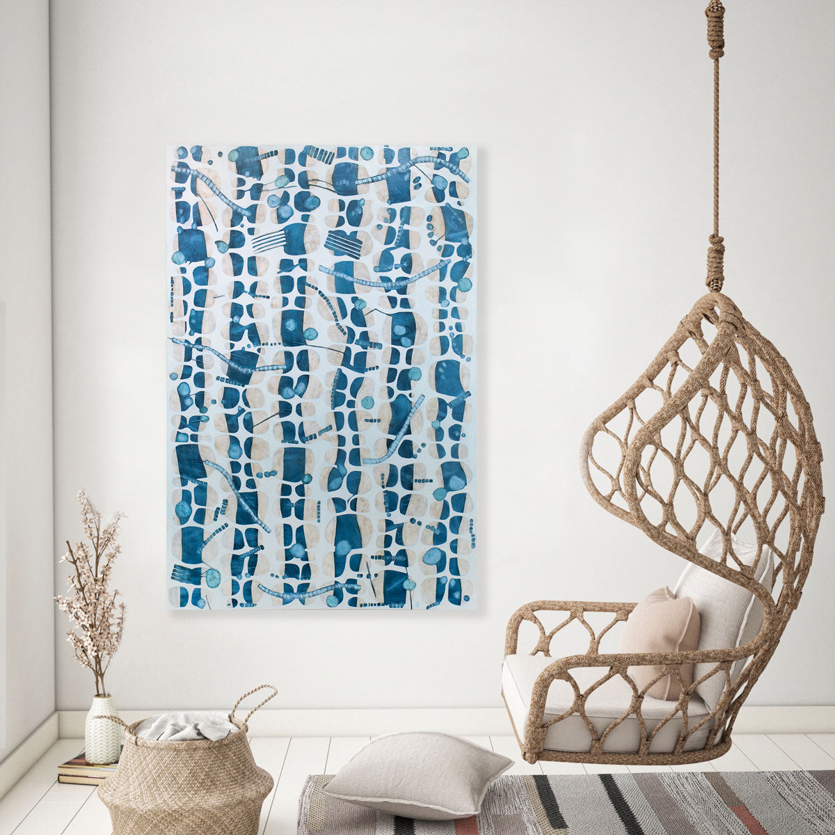 An abstract blue and white painting hangs on a white wall next to a hanging swing chair on the right.