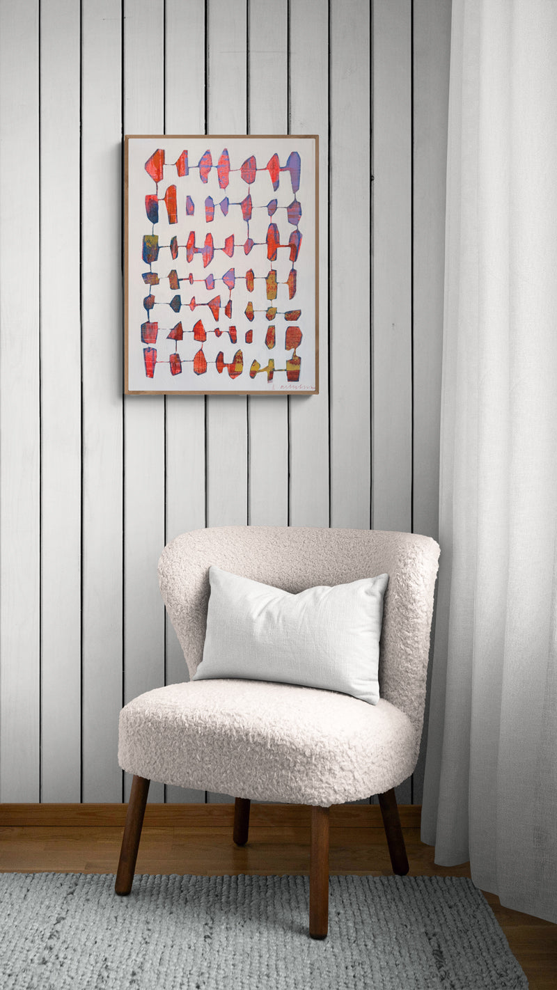 Chair with a white pillow against a gray paneled wall with a colorful abstract painting.