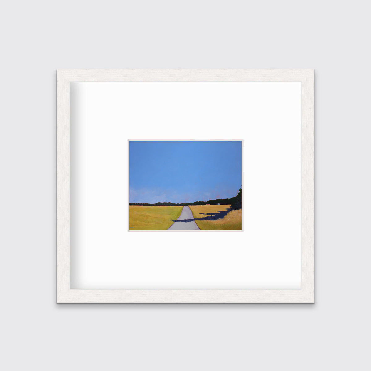 A blue and yellow-green abstract landscape print on paper, framed in a white wood frame hangs on a light wall.