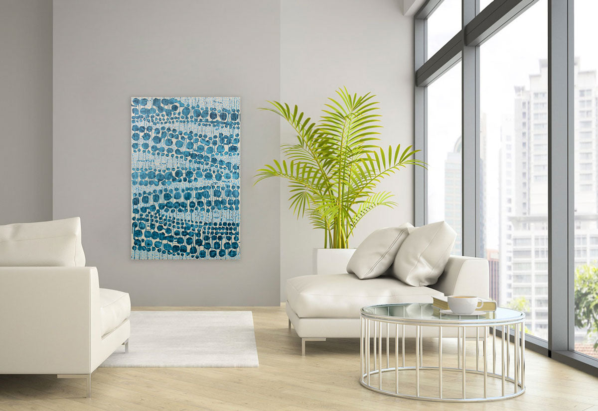 A blue and beige abstract painting hangs on a light grey wall above white leather sofas and next to a large potted floor plant.