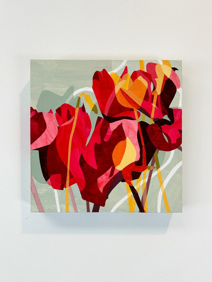 A colorful abstract floral artwork on a wall, featuring predominantly red and pink tones with touches of yellow and green hanging on a white wall.