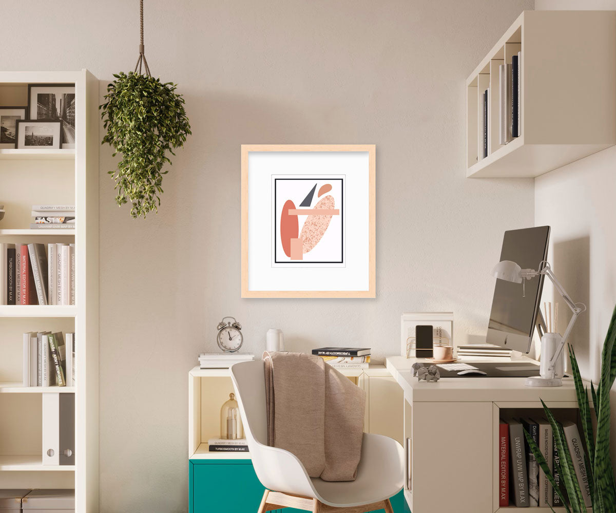A pink and grey abstract art print in a neutral frame hangs on a beige wall between a desk and bookcase.