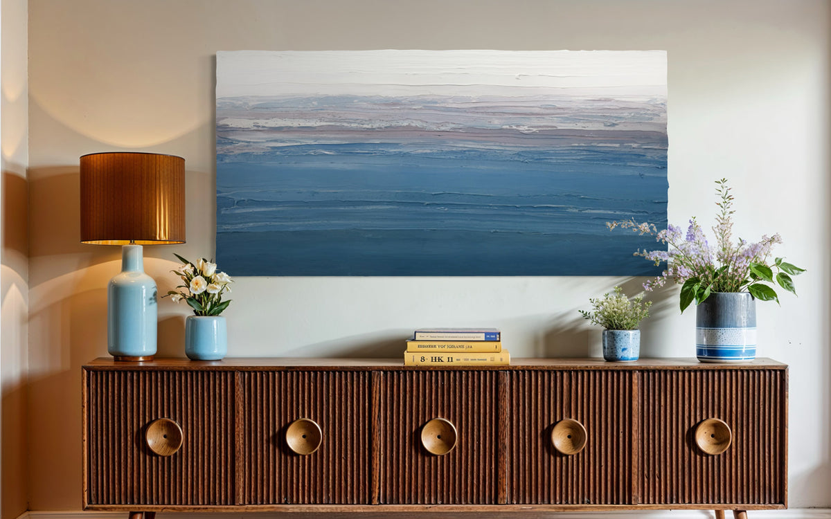 Wooden sideboard with decorative items against a wall with a large original abstract painting.