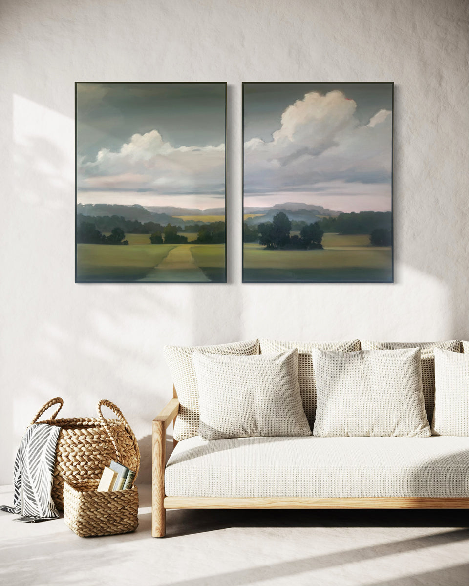 Two landscape paintings above a sofa in a living room.