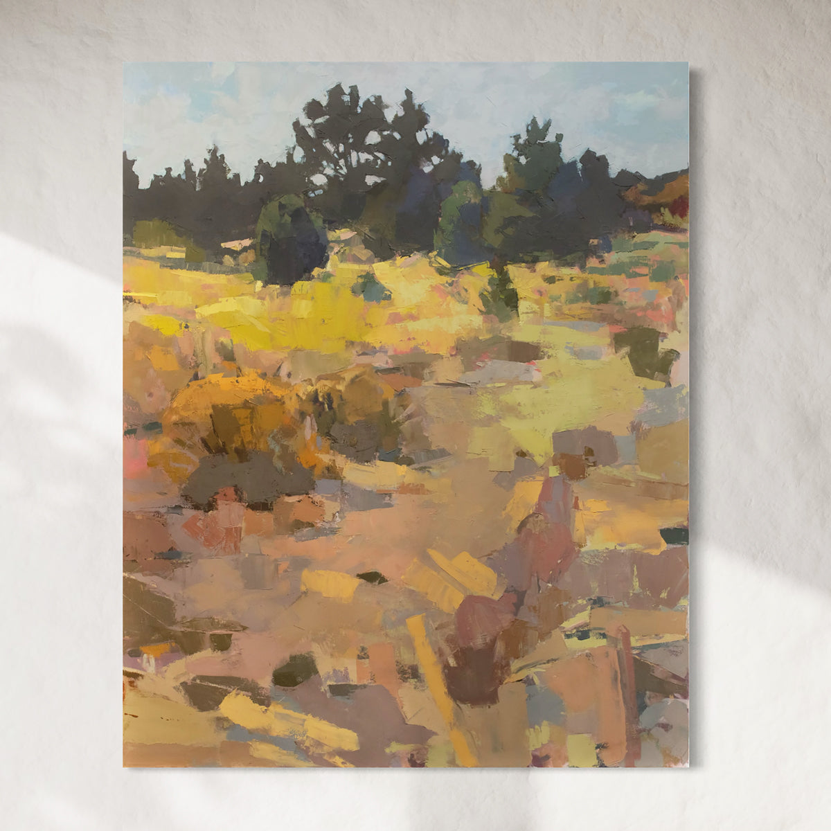 A warm-toned abstracted landscape painting hangs on a white wall.