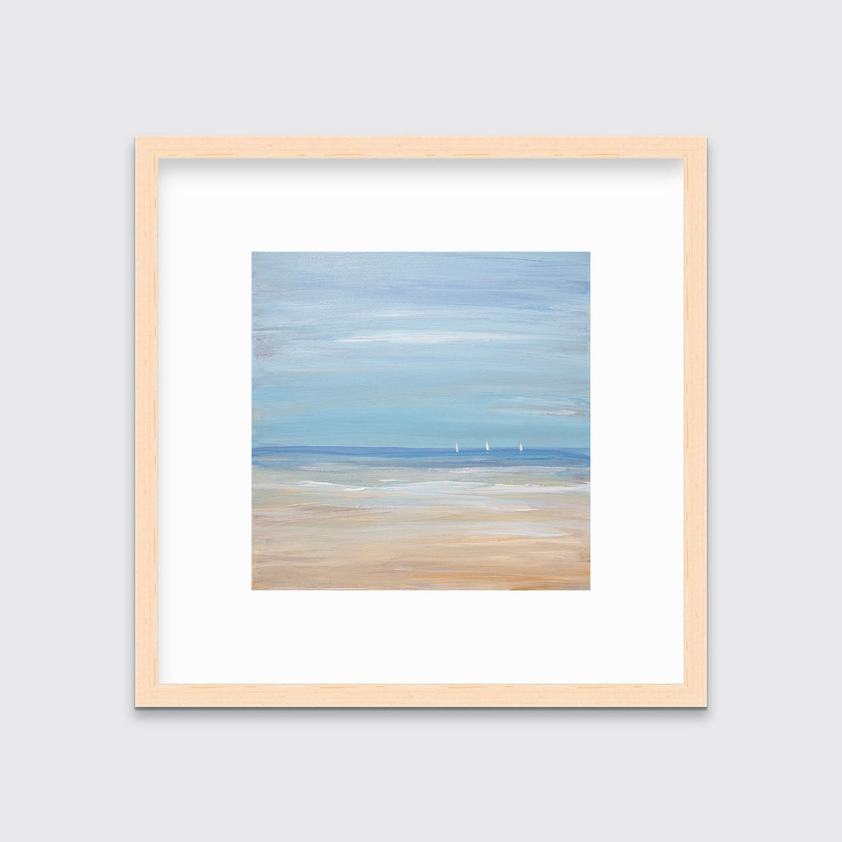 A blue, beige and white abstract seascape print with three small sailboats in a natural wood frame with a mat hangs on a white wall.