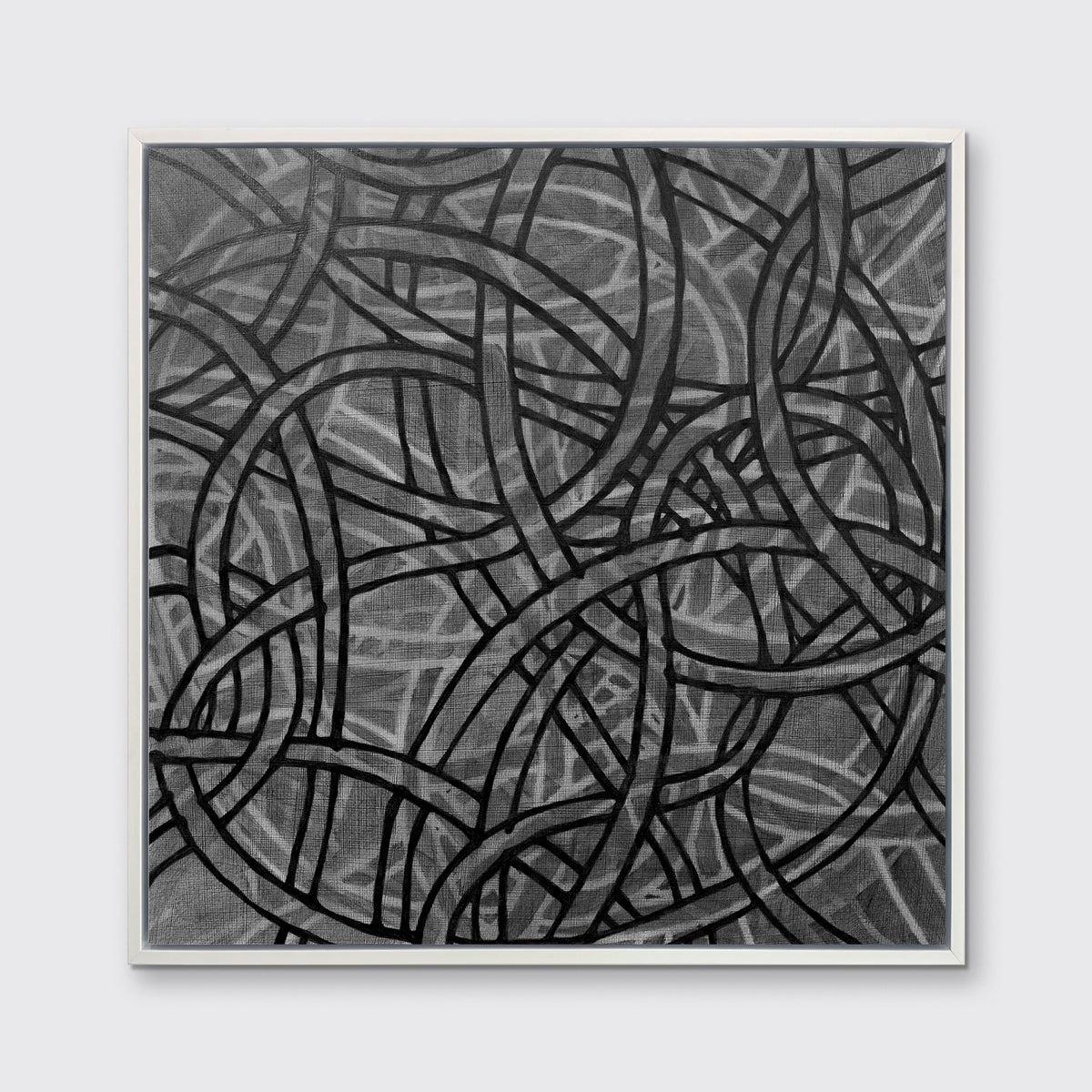 A black, grey and white abstract print in a white floater frame hangs on a white wall.