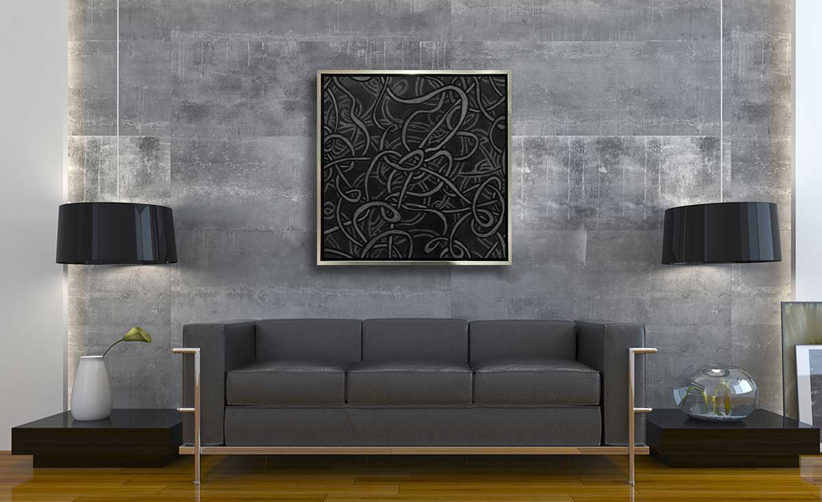 A grey and dark grey abstract print in a silver floater frame hangs on a light grey textured wall above a modern grey sofa, two matching hanging pendant lamps and two low black side tables.