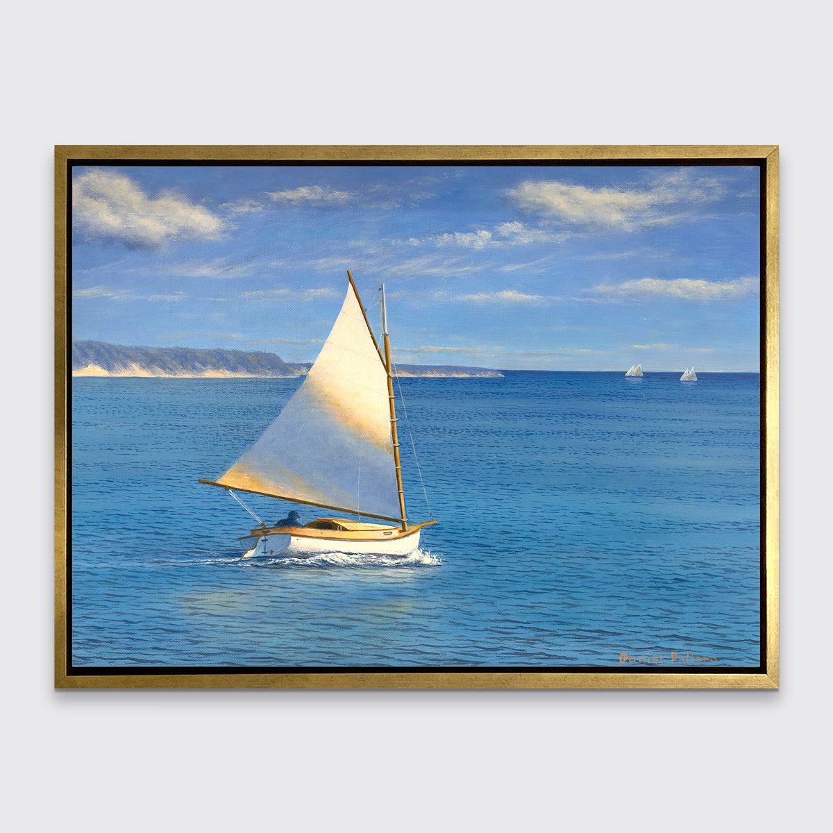A blue, beige and white realist seascape print with a sailboat in a gold floater frame hangs on a white wall.