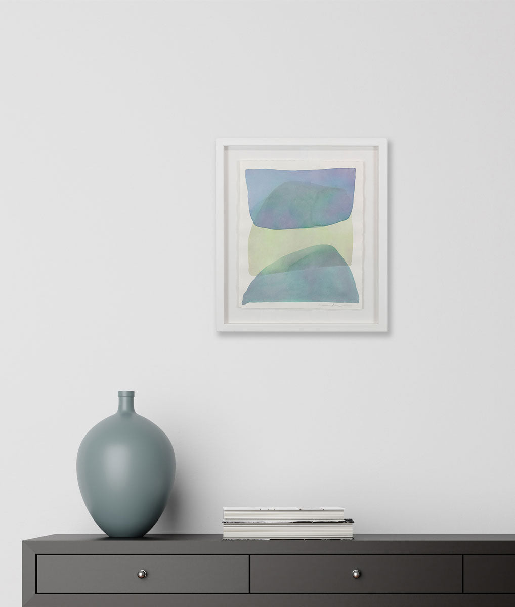 A watercolor of blue, green and dark turquoise forms overlapping is hung above a console table. Wired and ready to hang.