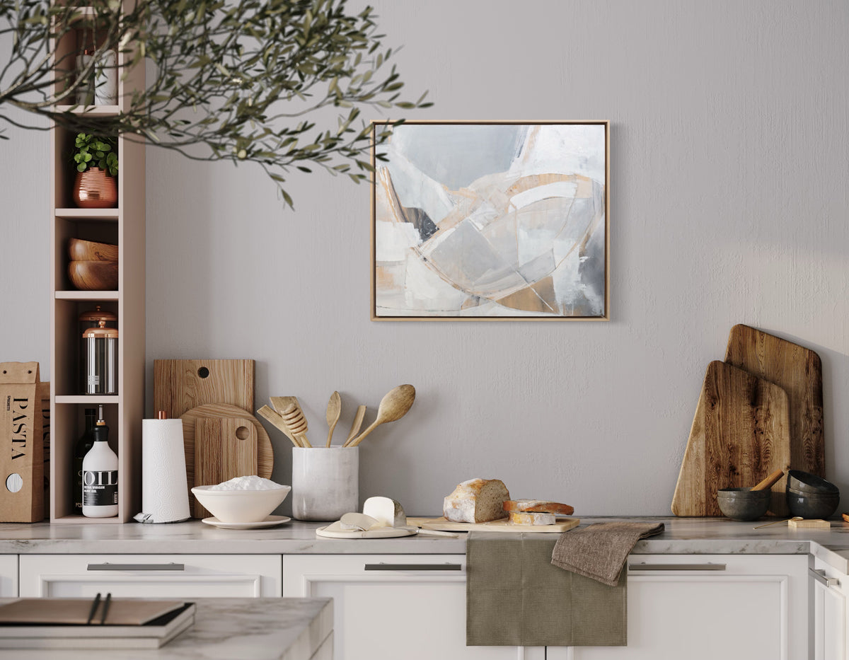 An abstract painting with white, orange and grey patches is hung in a kitchen. Wired and ready to hang.