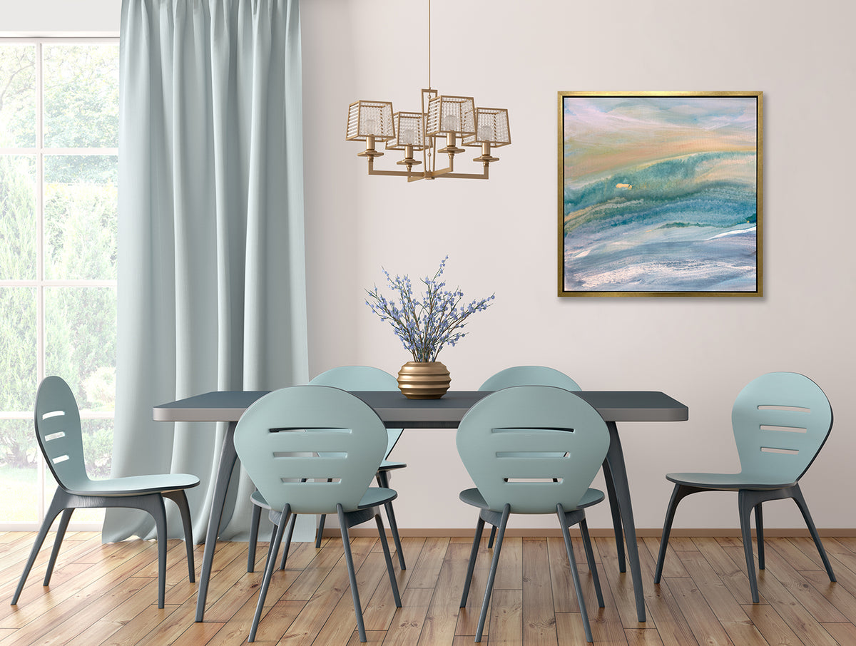 A blue, teal, yellow and white abstract print in a gold floater frame hangs on a white wall above a dark teal table with six light blue chairs.