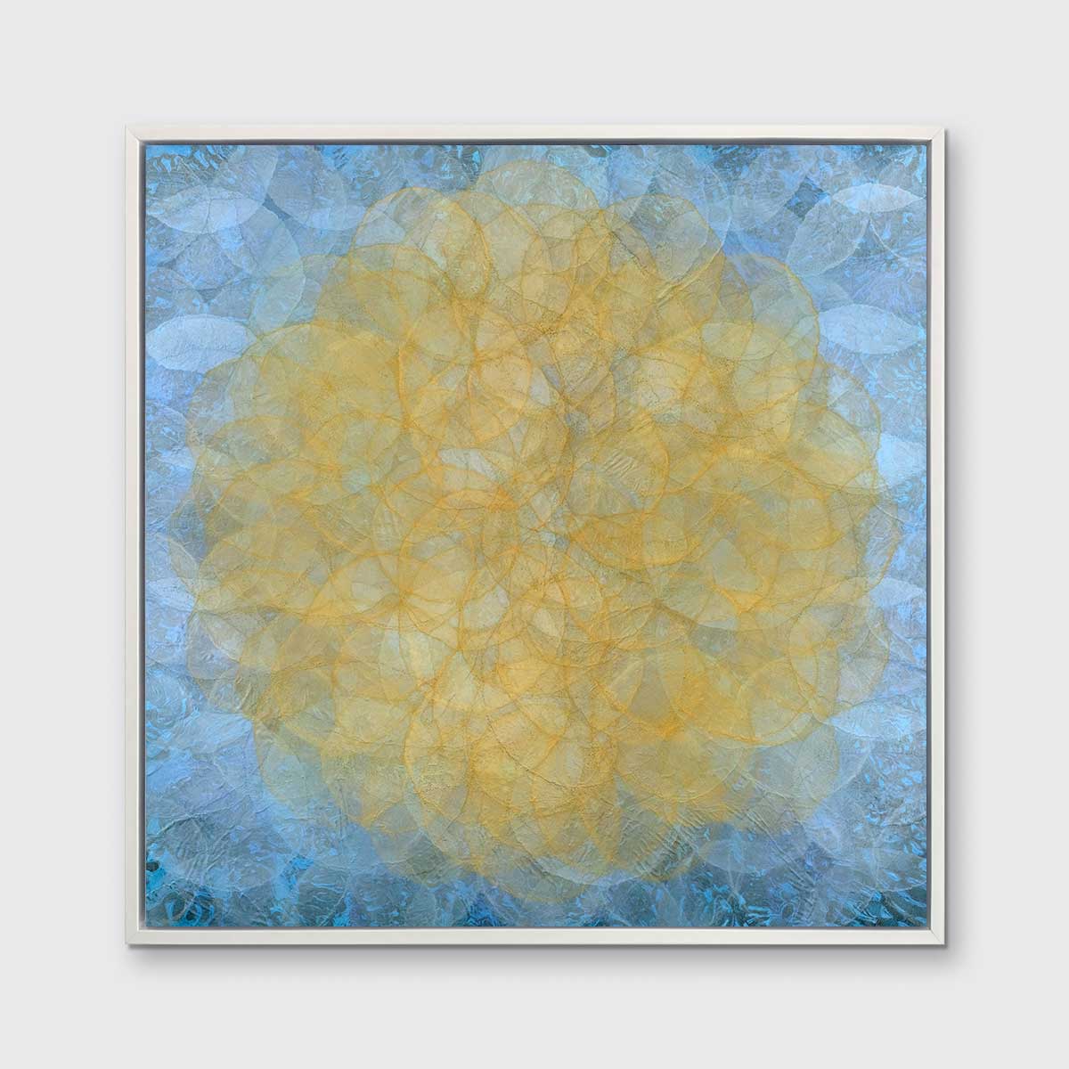 A blue, golden yellow and white abstract geometric print in a white floater frame hangs on a white wall.