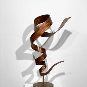 Spiral, abstract, steel sculpture with orange dye and wax sitting on a pedestal in front of a white wall.