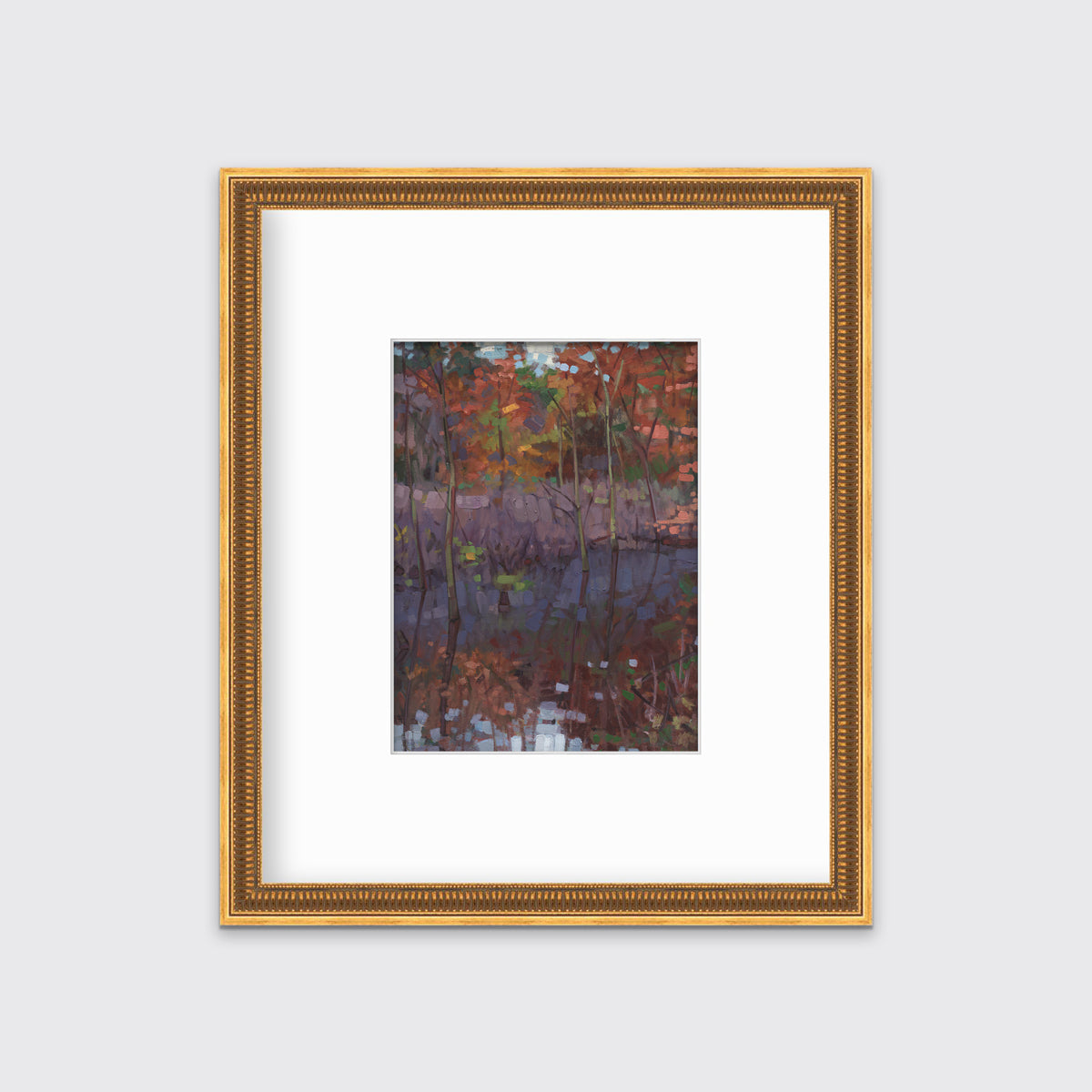 A muted multicolored abstract landscape print in a gold frame with antiqued beading with a mat hangs on a white wall.