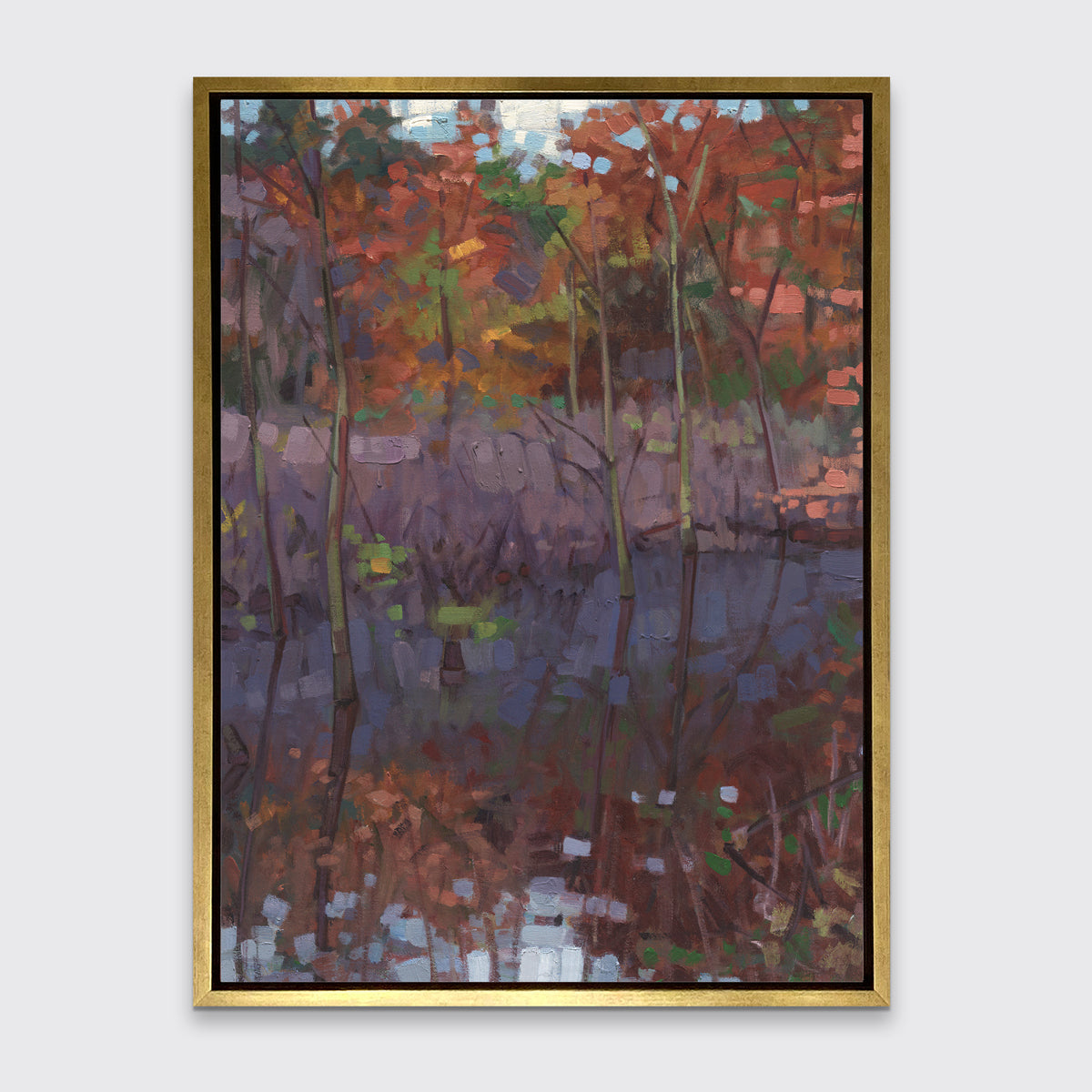 A muted multicolored abstract landscape print in a gold floater frame hangs on a white wall.